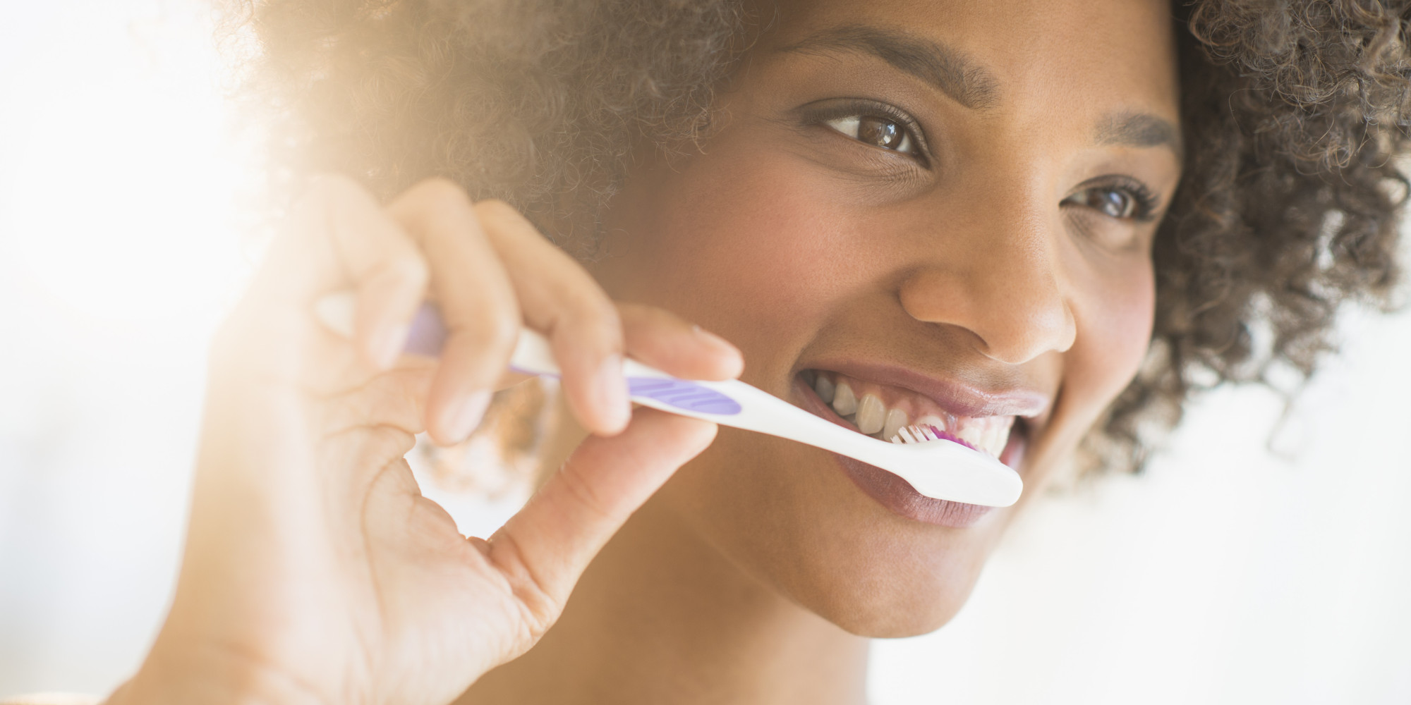 Beauty portrait of woman brushing teeth, studio shot